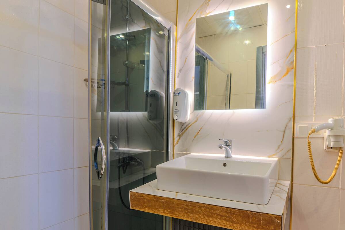 A bathroom with a glass-enclosed shower, a white sink with a wooden countertop, and a mirror above the sink.