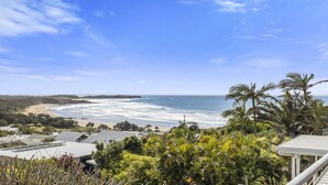 A coastal view with a beach, ocean, and residential area with houses and vegetation.