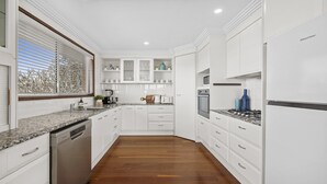 A modern kitchen with white cabinetry, a granite countertop, and a wood floor.