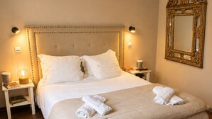Ein Hotelzimmer mit einem großen Bett, zwei Nachttischen, einem Wandspiegel und einem Fenster.
