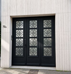 A black double door with geometric glass patterns and the letter 'A' on a building facade.