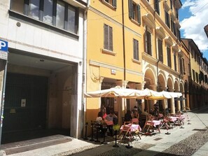 Ett café vid gatan med uteservering, en gul byggnad och en väl synlig skylt för en restaurang.
