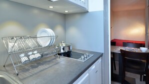 A compact kitchen with a dish rack, a microwave, a stove, and a dining area with a table and chairs.