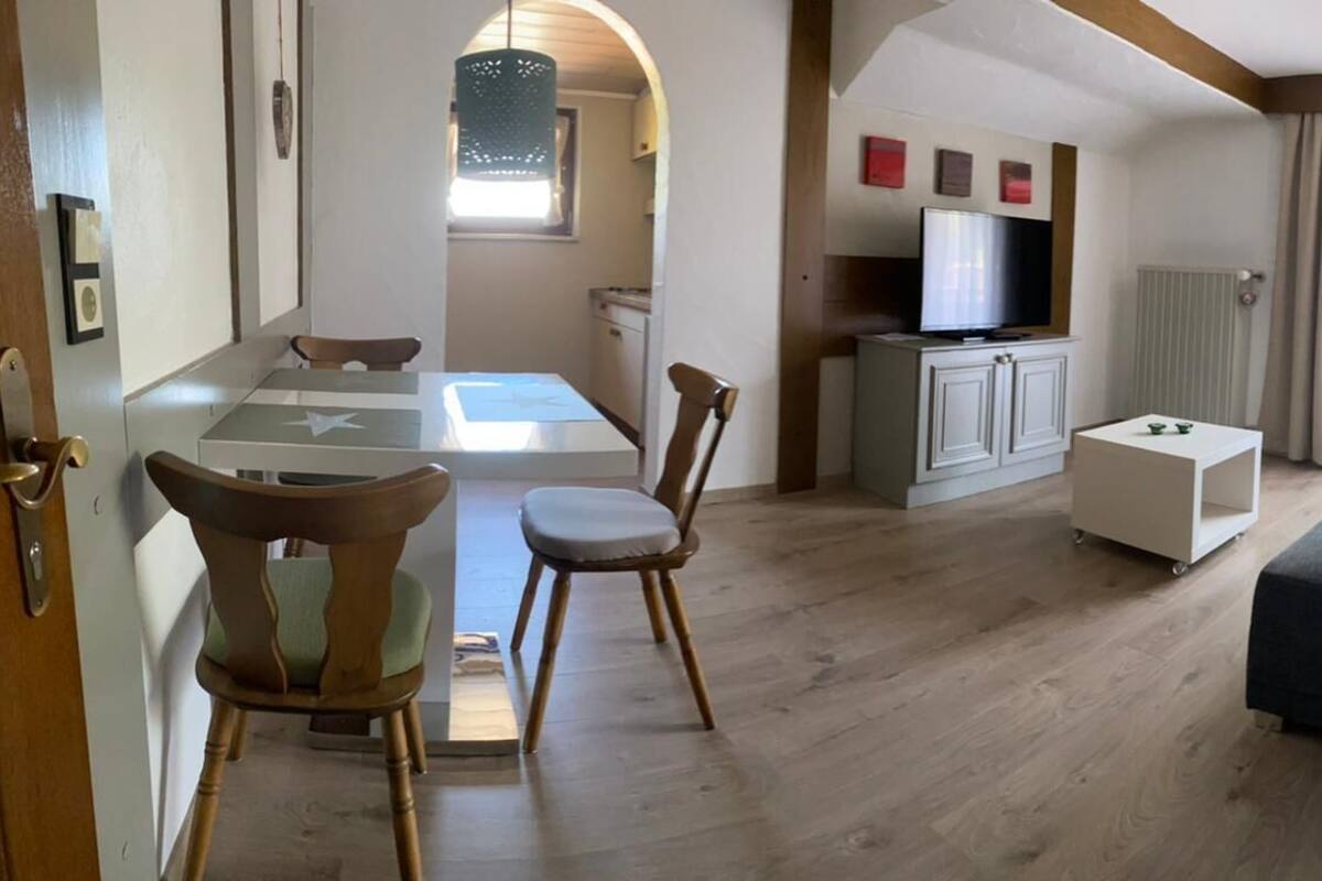 A living room with a sofa, a TV, and a dining area with chairs and a table.