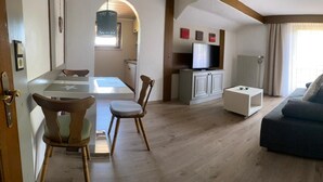 Una sala de estar con sofá, televisión y un comedor con sillas y mesa.