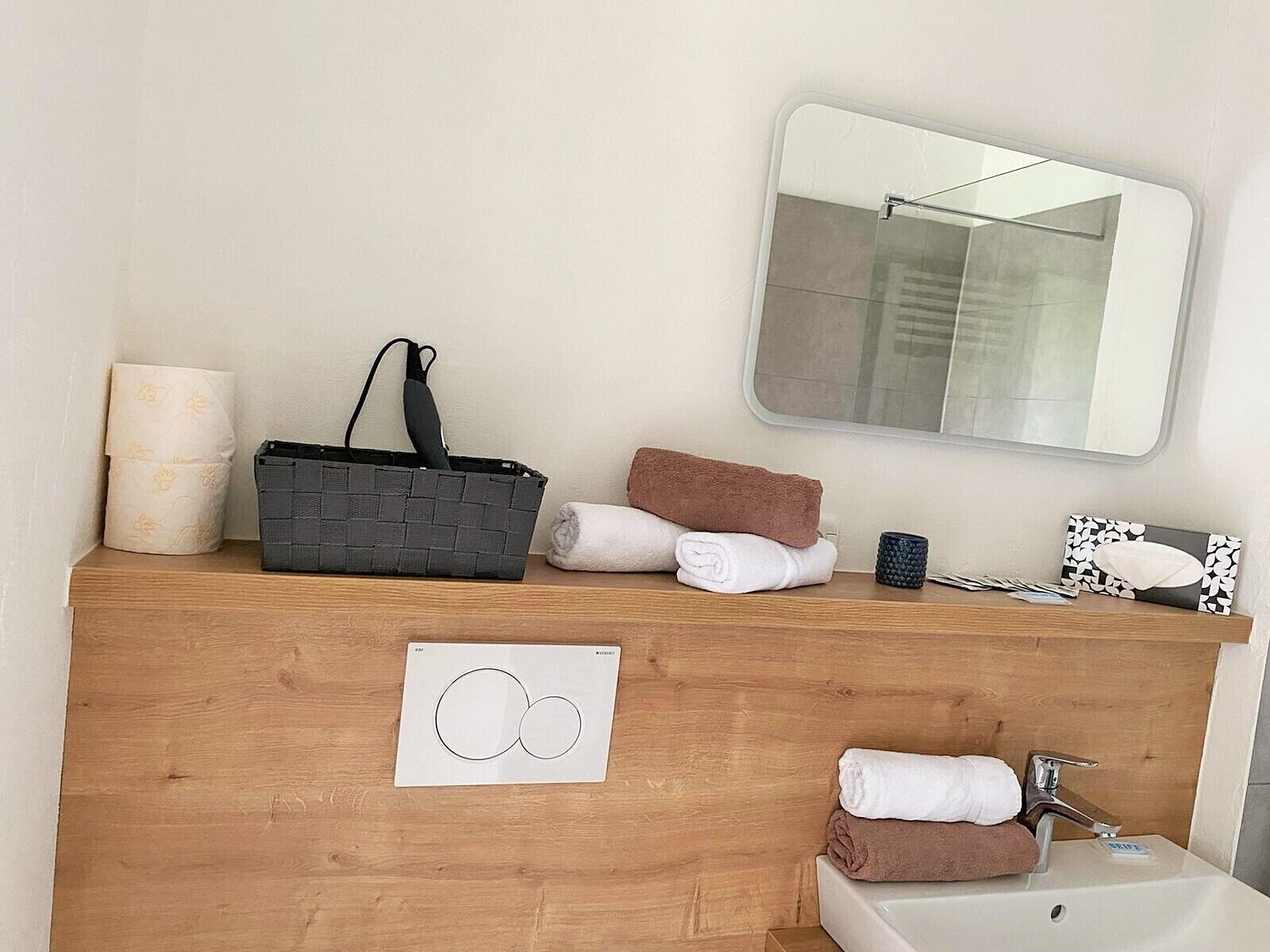 A bathroom with a wooden vanity, a mirror, a sink, and towels.