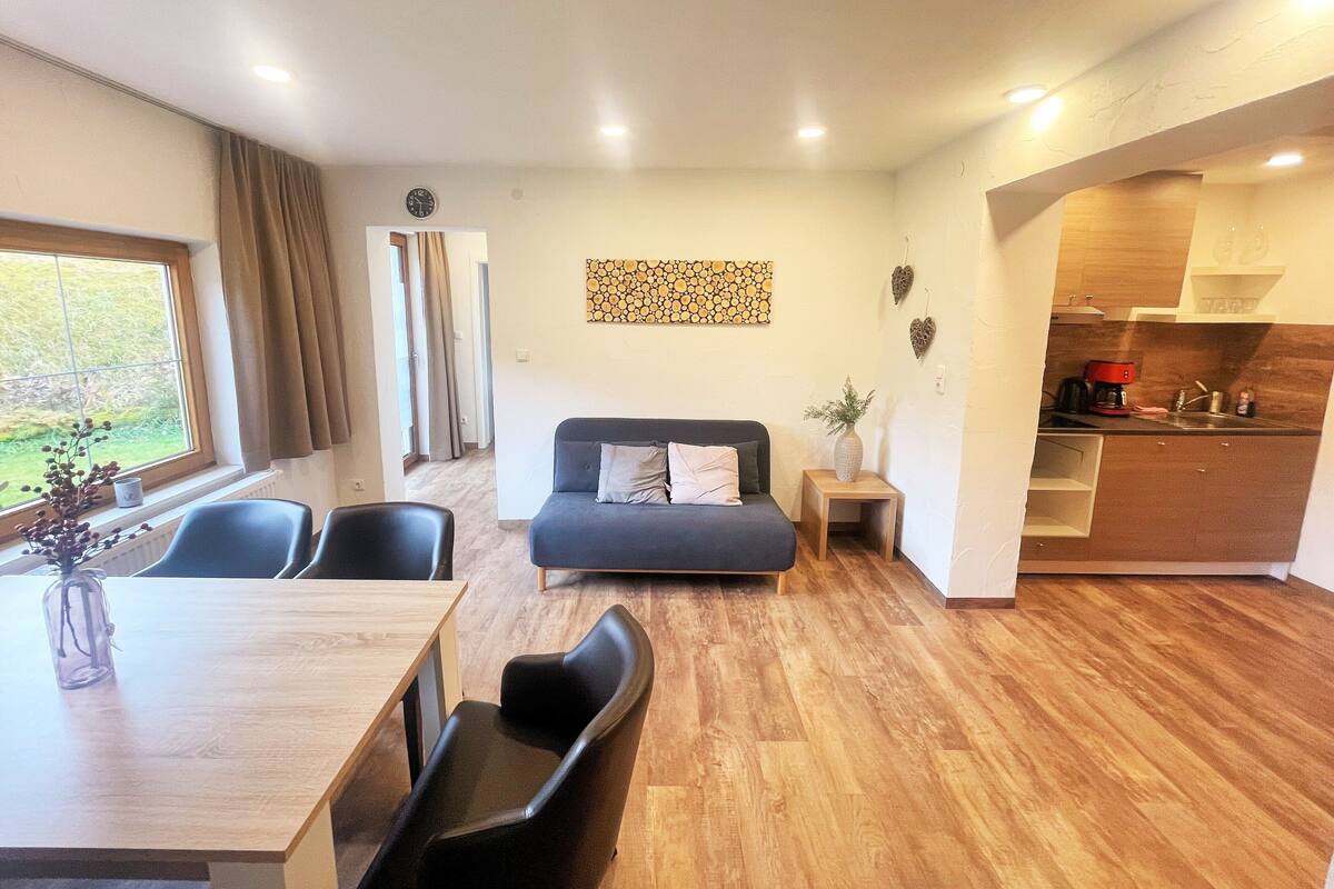 A modern living space with a sofa, dining table, and kitchen area.