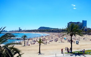 Praia movimentada com palmeiras e céu azul límpido.
