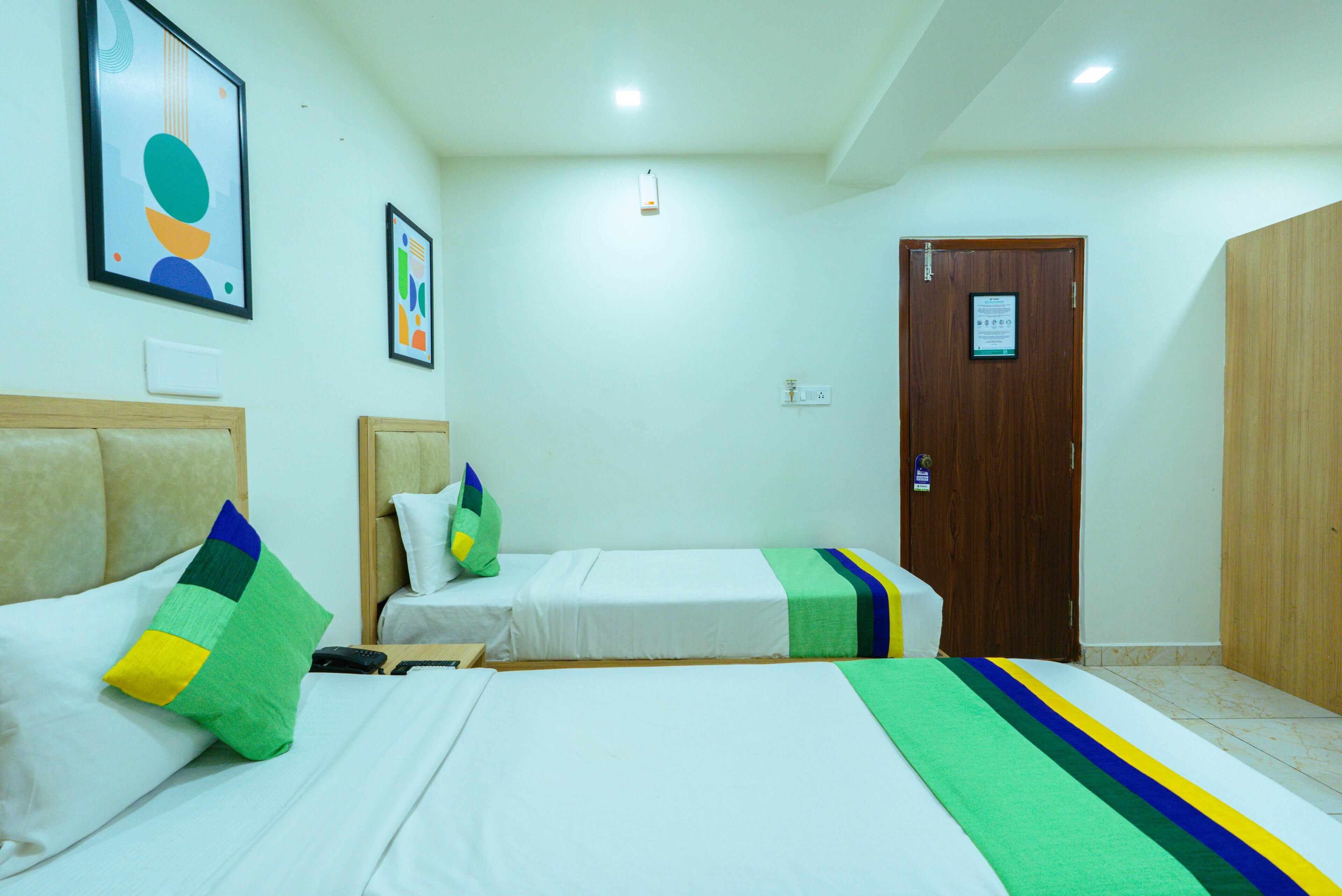 Habitación de hotel con dos camas individuales, un armario de madera y una puerta con un cartel.
