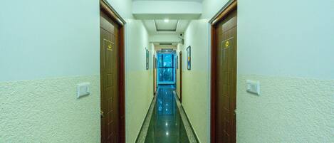 A hallway with wooden doors, white walls, and a tiled floor.