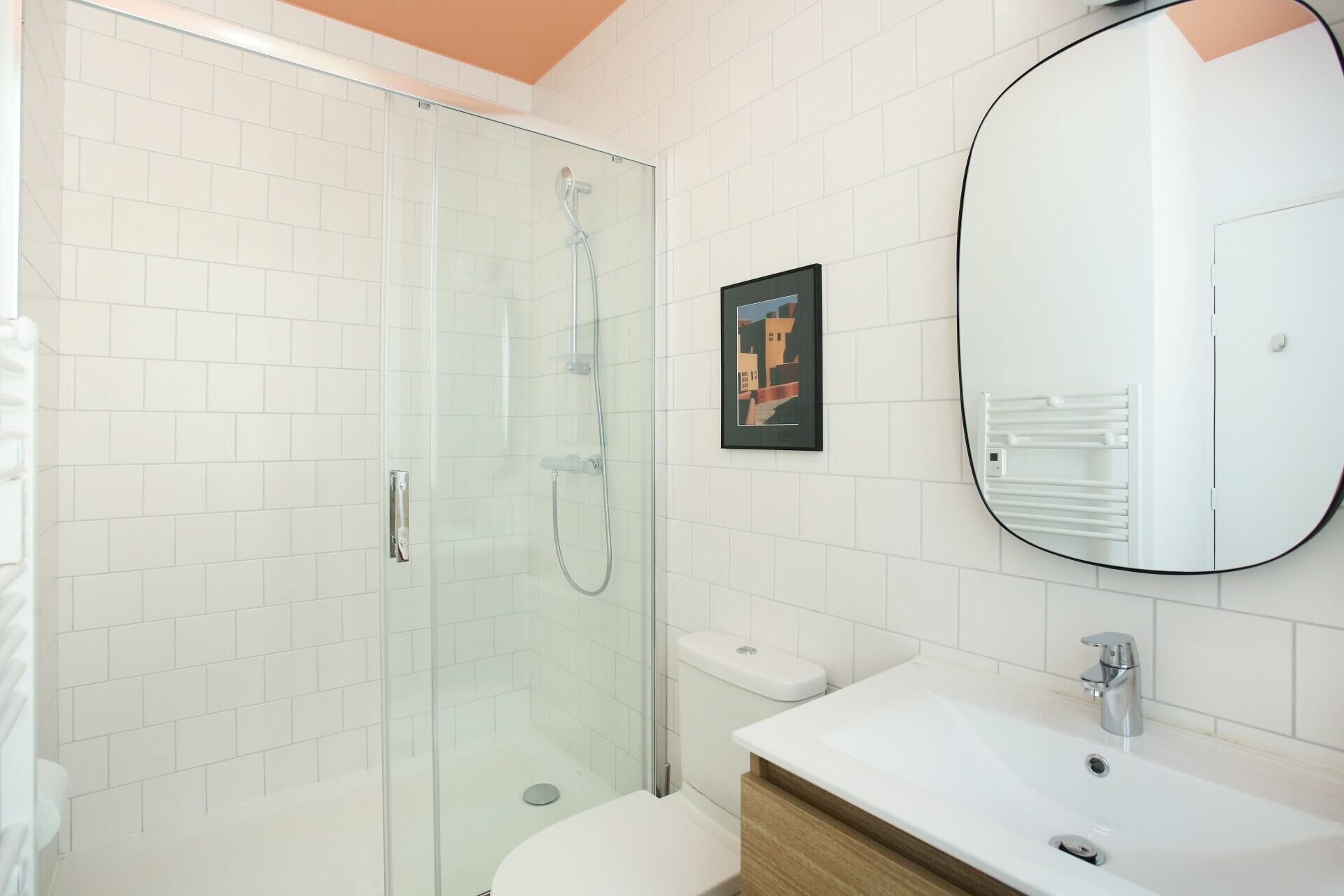 A modern bathroom with a glass-enclosed shower, a white toilet, and a sink with a mirror.