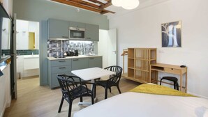Un studio compact comprenant un coin cuisine, un espace repas et un lit.