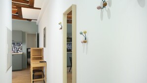 Un couloir avec une chaise en bois, un bureau et un miroir au mur.