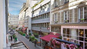 Une vue de rue avec un bâtiment sur lequel on peut voir une enseigne « LUNA », des tables et des chaises à l’extérieur, et un escalier menant à un étage supérieur.