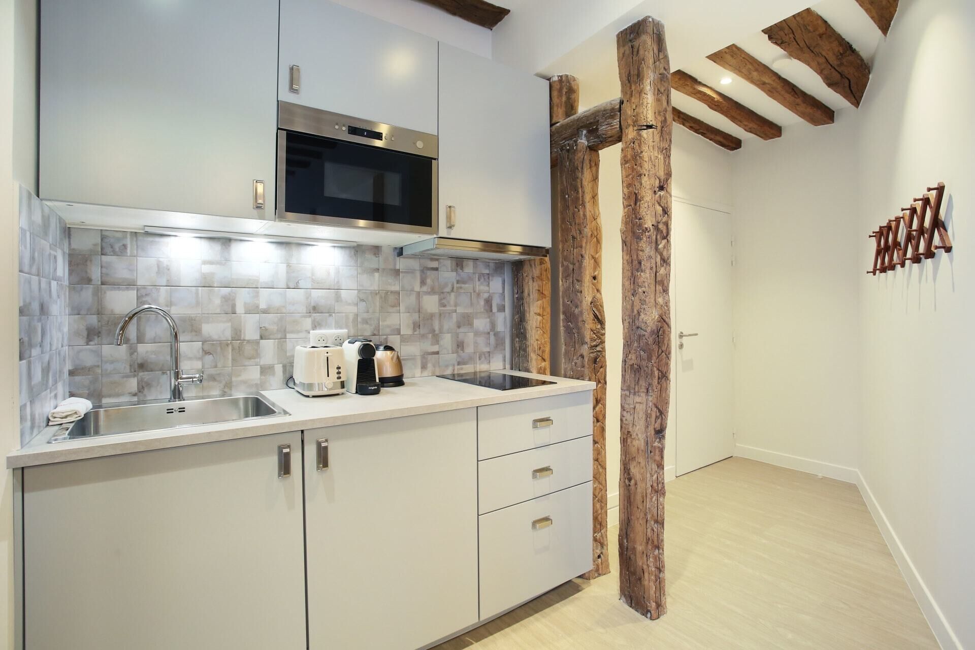A modern kitchen with a stainless steel microwave, a built-in oven, a sink with a faucet, and a countertop with a toaster and a coffee maker.