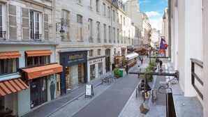 A narrow street with buildings on either side, featuring storefronts like 'APERTIVUS' and 'LE PAPIERON'. - Cadet 104 - One Bedroom Apartment, Sleeps 4 (Paris)
