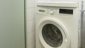 A compact, modern laundry room with a front-loading washing machine and a wall-mounted dryer. - Cadet 104 - One Bedroom Apartment, Sleeps 4 (Paris)