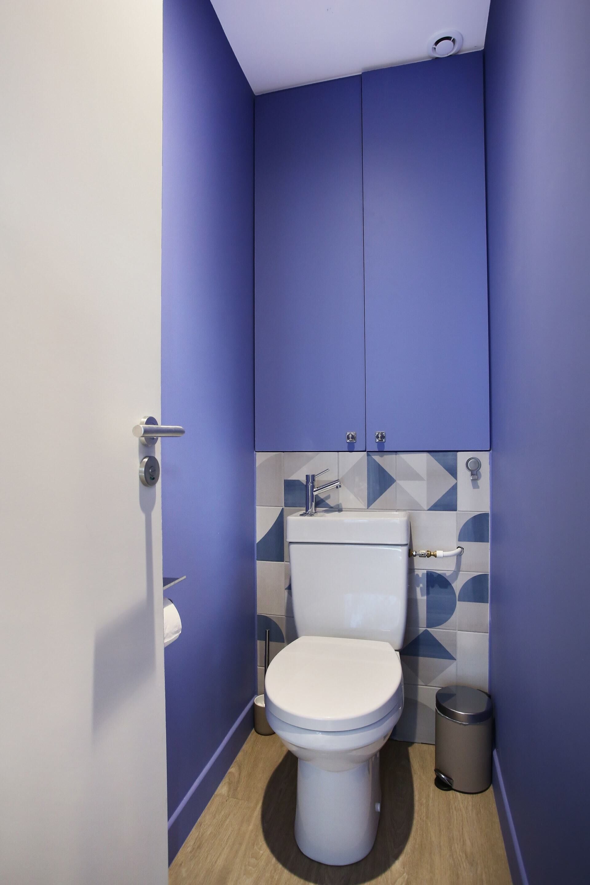 Un baño pequeño con inodoro blanco, lavamanos y un cubo de basura.