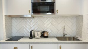 A kitchen with a stainless steel oven, a microwave, a kettle, a toaster, and a sink.