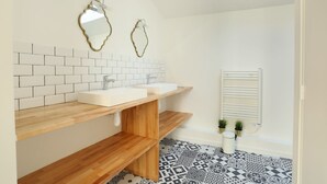Uma casa de banho moderna com duas bacias, estantes de madeira, um chão estampado e um radiador.