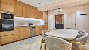 A modern kitchen with built-in appliances, a dining area with a table and chairs, and a door with a view. - Caire 3 - One Bedroom Apartment, Sleeps 6 (Paris)