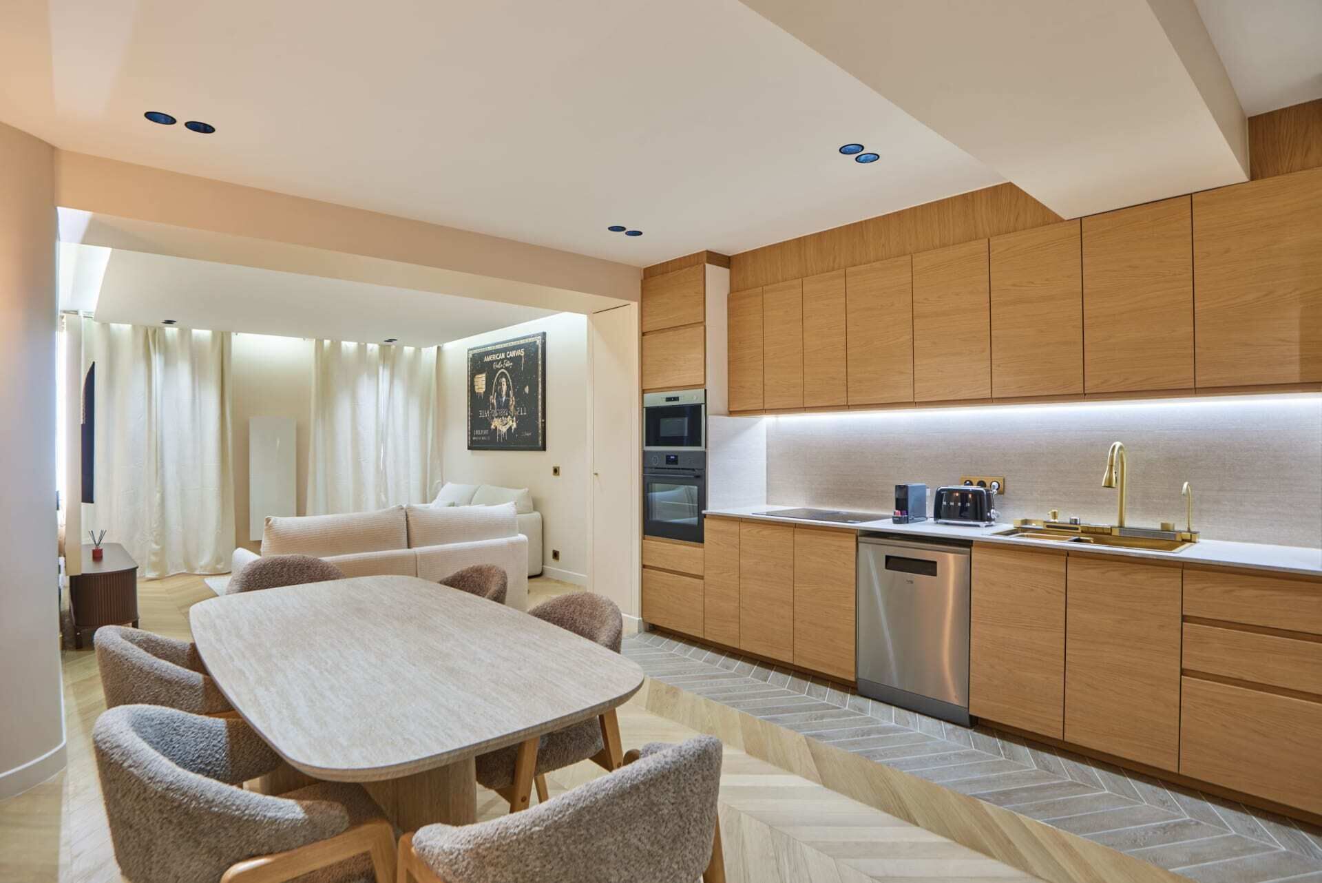 Una cocina moderna con armarios de madera, lavavajillas de acero inoxidable y horno empotrado.