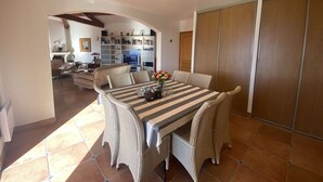 Un comedor con mesa a rayas y sillas de mimbre, una cocina al fondo y un armario con puerta corredera.