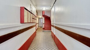 A hallway with lockers on one side and a red staircase on the other. - Caire 5 - Studio Apartment, Sleeps 2 (Paris)