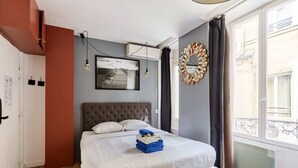 A bedroom with a bed, a picture on the wall, and a window with curtains. - Caire 5 - Studio Apartment, Sleeps 2 (Paris)