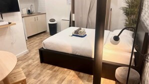 A compact hotel room with a bed, bedside table, and a small round table. - Charon 2 - Studio Apartment, Sleeps 2 (Paris)