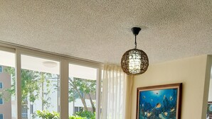 Zona pranzo con tavolo rotondo, sedie, lampadario e un quadro appeso al muro.