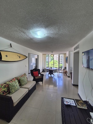 A living room with a sofa, a dining table, and a TV.