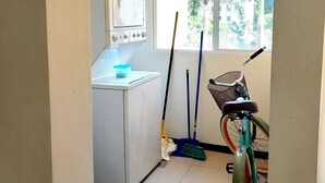 Una lavanderia con lavatrice, scopa, mocio e bicicletta.