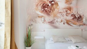 A modern hotel room with a large bed, a potted plant, and a wall with a decorative design.