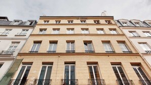 A multi-story building with a symmetrical facade, evenly spaced windows, and balconies with wrought iron railings.