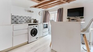 Una cocina moderna con lavadora, microondas y televisor de pantalla plana montado en la pared.