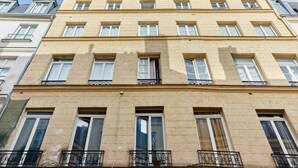 Un edificio de varios pisos con un estilo arquitectónico clásico, que presenta ventanas y balcones con barandillas de metal regularmente espaciados.
