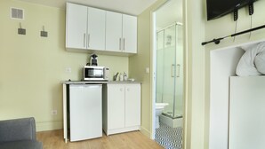 A compact kitchen with a microwave, small refrigerator, and white cabinets. - Cosy Studio - Studio Apartment, Sleeps 2 (Paris)