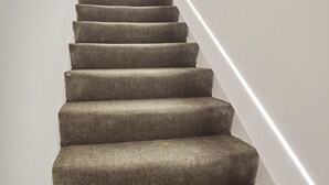 Eine Treppe mit einem strukturierten Teppich und einer weißen Akzentwand.