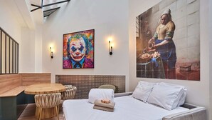 Ein Hotelzimmer mit einem Bett, einem runden Holztisch, zwei Stühlen, einem Kopfteil und zwei Wandleuchten.