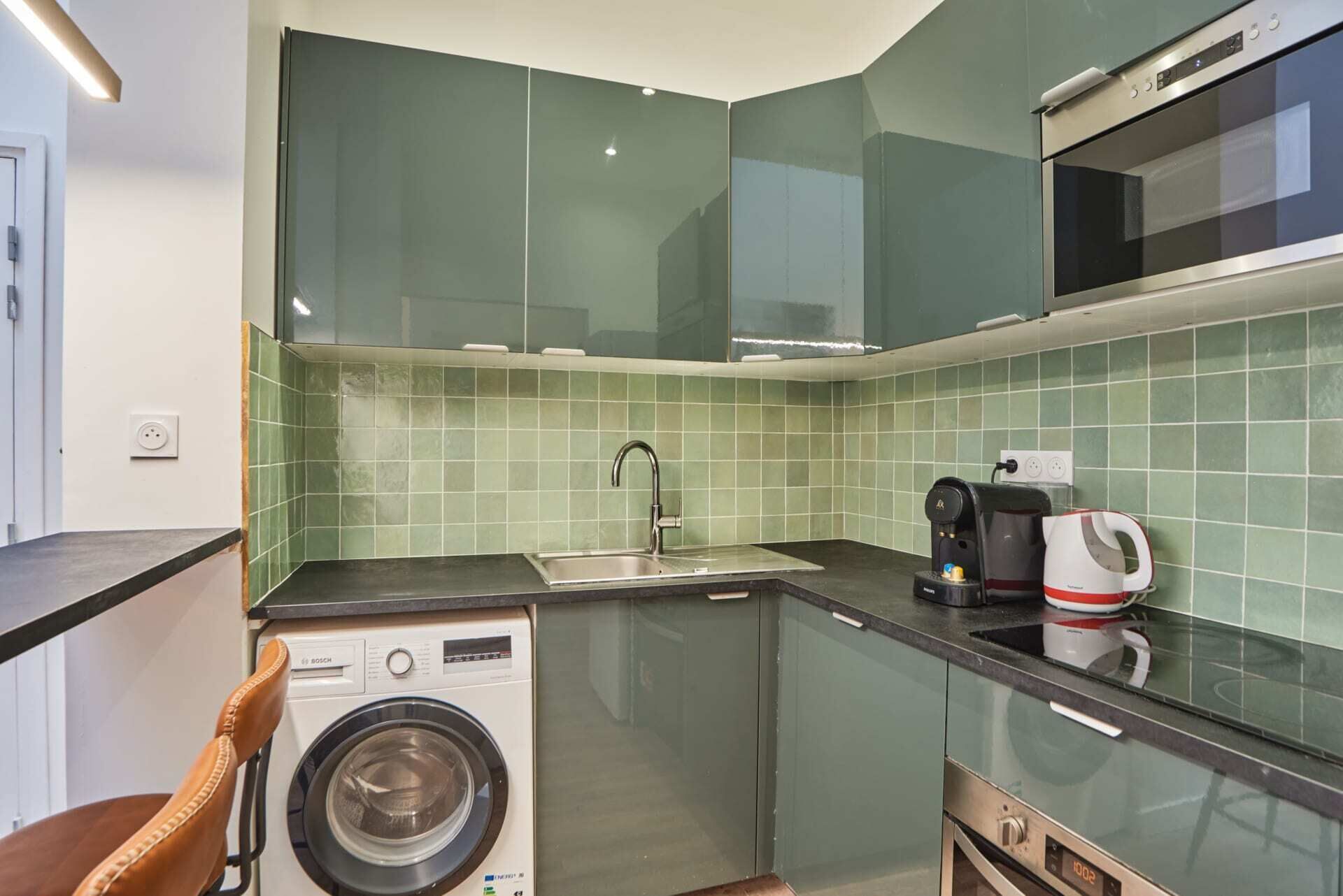 Una cocina compacta con lavadora, cafetera y microondas.