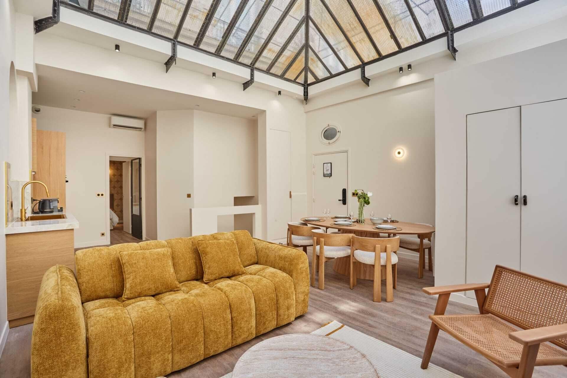 Une pièce spacieuse avec un plafond haut, un coin repas et un canapé.