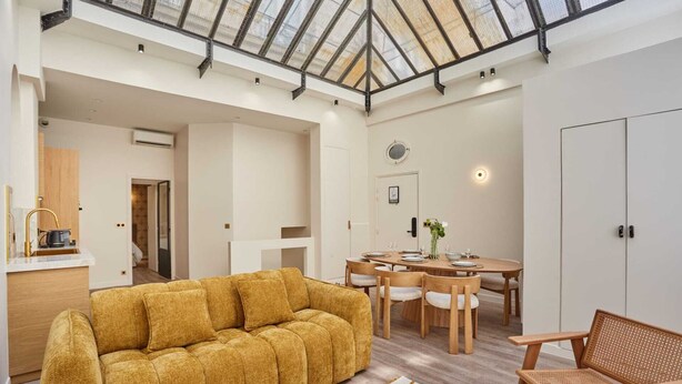 Una habitación amplia con techo alto, comedor y sofá.