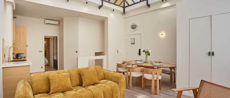 A spacious room with a high ceiling, a dining area, and a sofa.