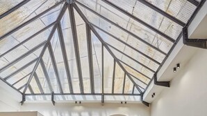 A spacious room with a high ceiling, a large TV, a sofa, and a dining area with chairs and a table. - Meslay 3 - Two Bedroom Apartment, Sleeps 6 (Paris)