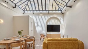 A modern living space with a dining area, a sofa, and a TV. - Meslay 3 - Two Bedroom Apartment, Sleeps 6 (Paris)