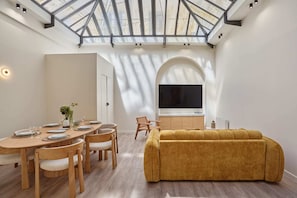 A modern living space with a dining area, a sofa, and a TV. - Meslay 3 - Two Bedroom Apartment, Sleeps 6 (Paris)