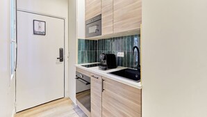Une cuisine compacte équipée d’un four à micro-ondes, d’une machine à café et d’un évier.