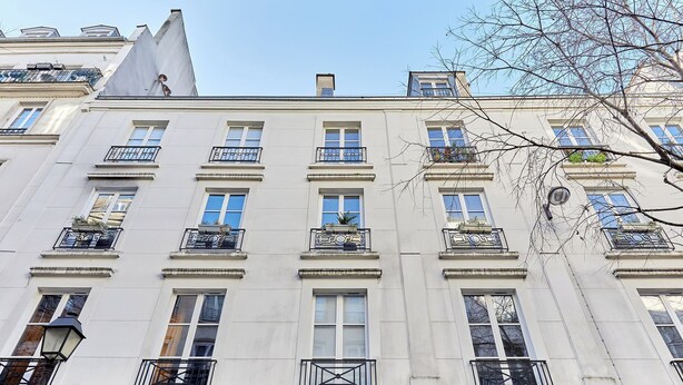 Un immeuble à plusieurs étages doté de balcons, de grandes fenêtres et surplombant un ciel dégagé.