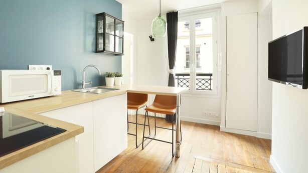 A compact kitchen with a microwave, sink, and bar stools. - Meslay 8 - Studio Apartment, Sleeps 2 (Paris)
